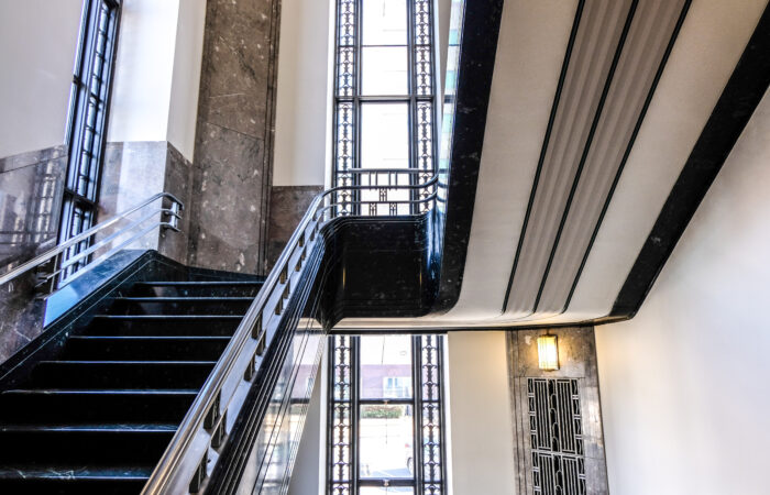Rising staircase in front of floor to ceiling window with metal detailing.