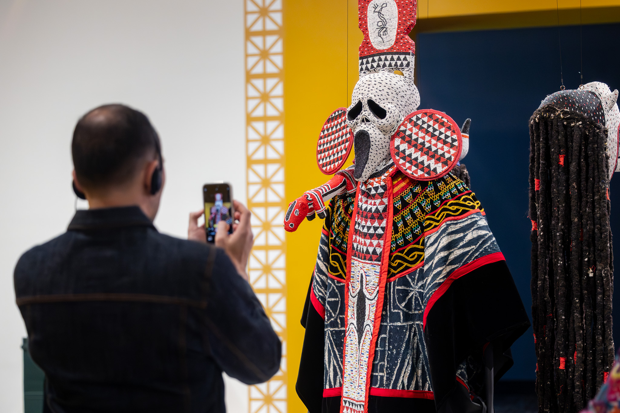 Man taking a photo of a masquerade ensemble