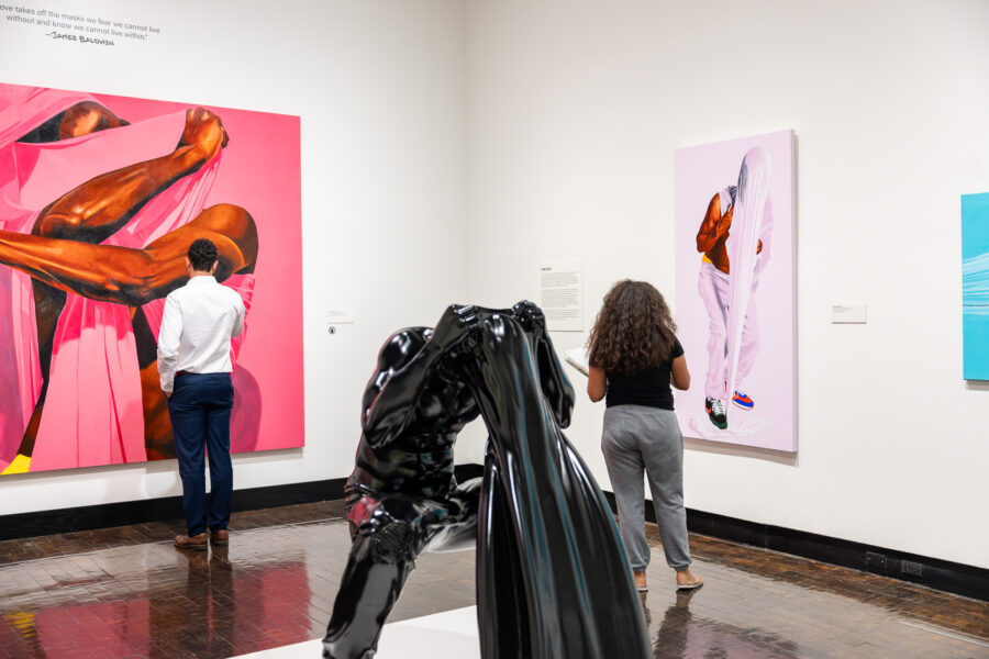 People looking at paintings in a gallery with a black sculpture in the foreground