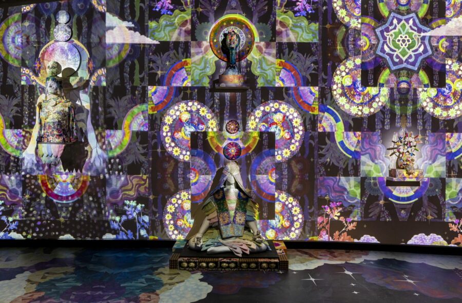 A bright colored projection of kaleidoscope shapes with a human form in the middle.