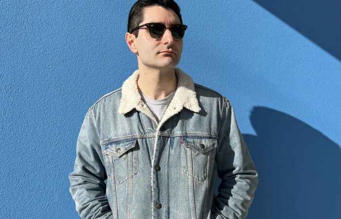 Photo of Adam Paul in a jean jacket and sunglasses.