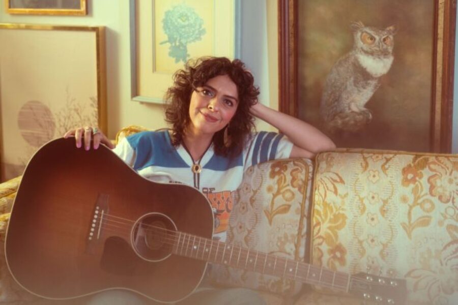 Raihanna Estrada poses on a couch with her guitar