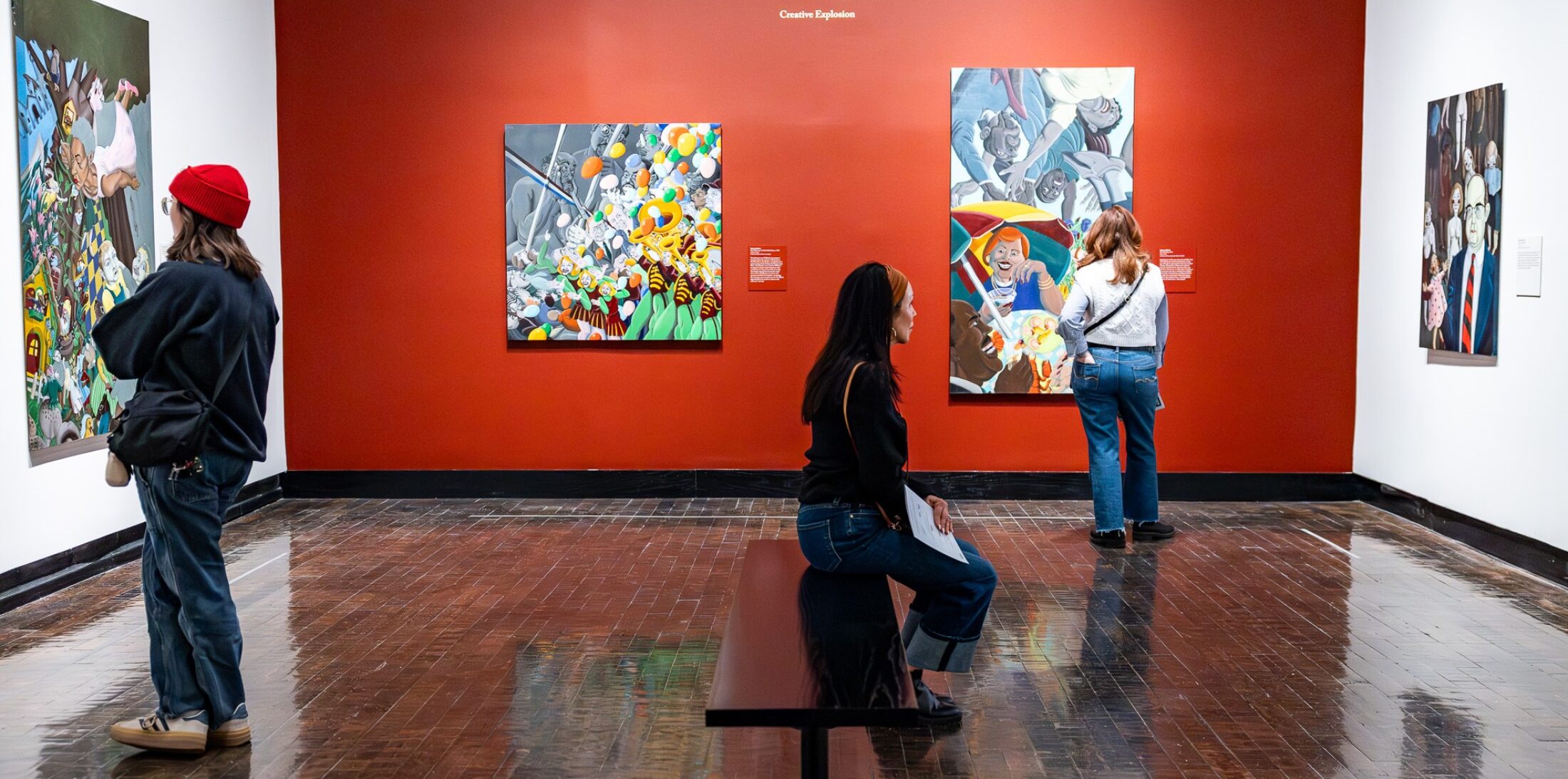 Three people looking at artwork in a gallery.