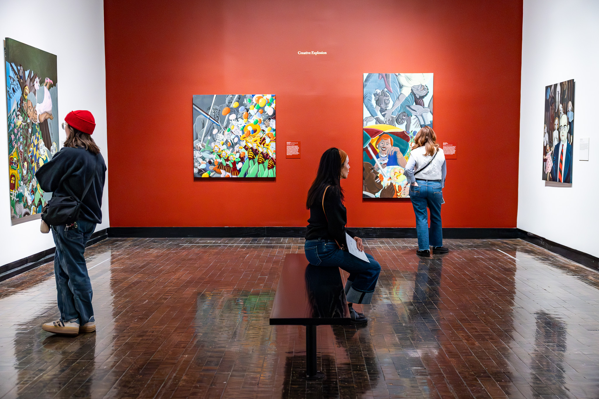 Three people looking at artwork in a gallery.