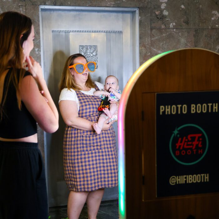 Mom wearing large prop sunglasses holding her baby getting picture made