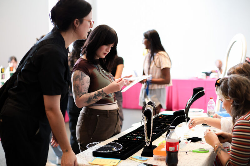Teens stand around a jewelry vendor
