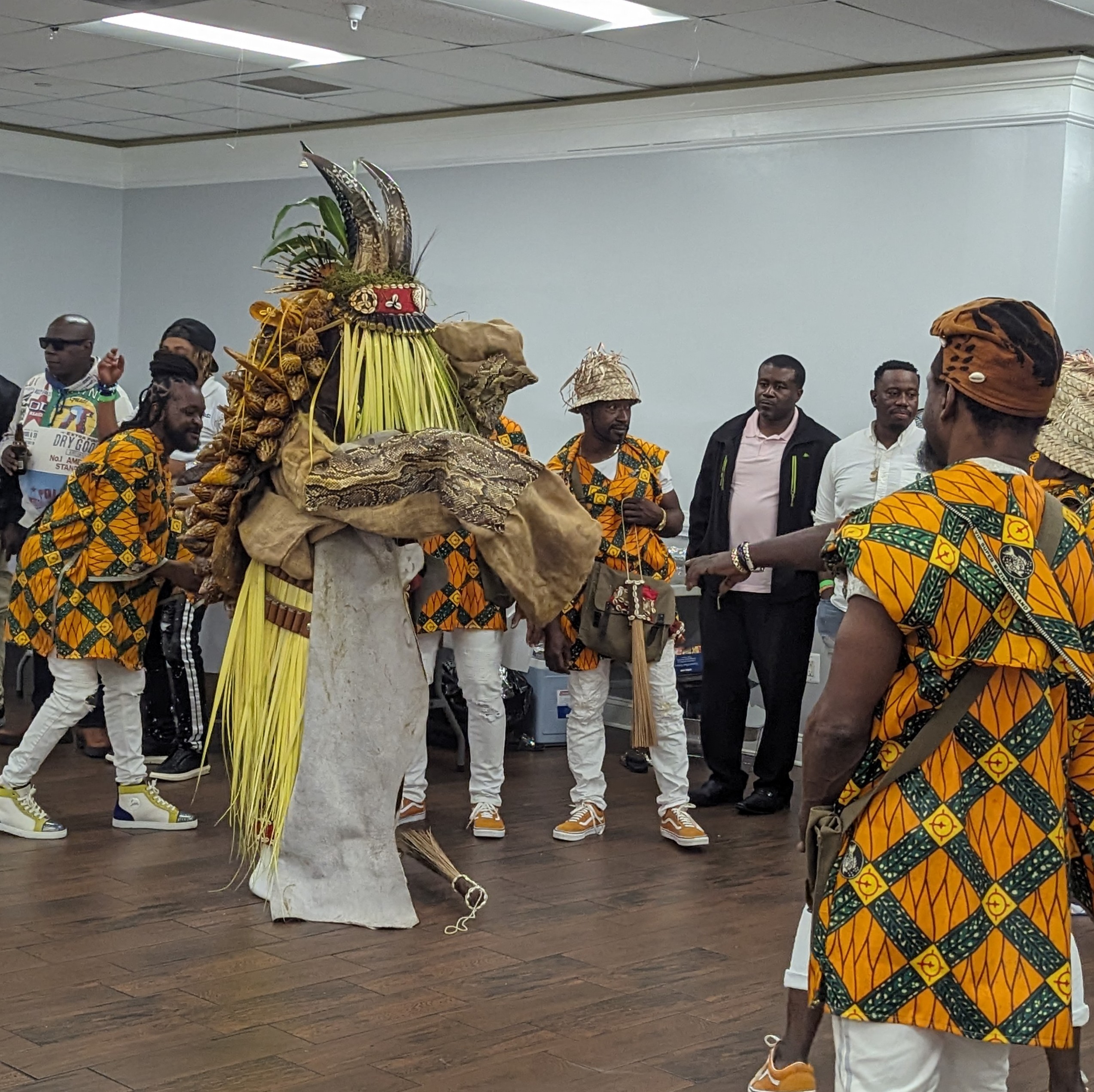 Group of men huddled around a masquerade 