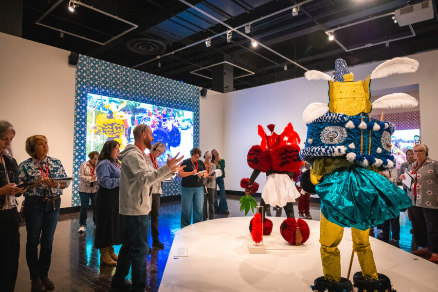 A man guides a tour of African Masquerades in an art museum.