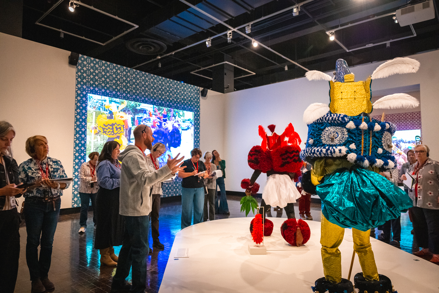 A man guides a tour of African Masquerades in an art museum.