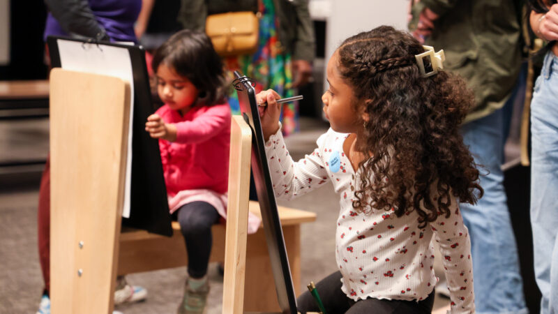 Two young girls sitting at art easels drawing