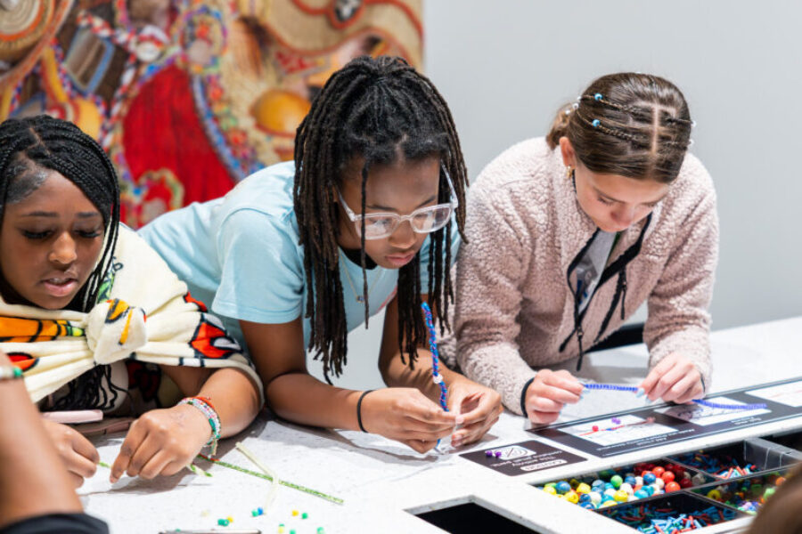 Three girls work on a craft at an art station.