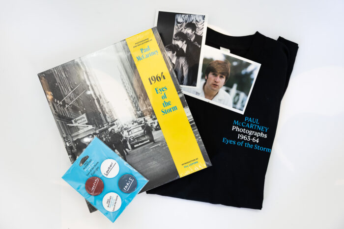 Assortment of merchandise from the Paul McCartney Photographs exhibition including a catalogue, shirt, buttons, and postcard