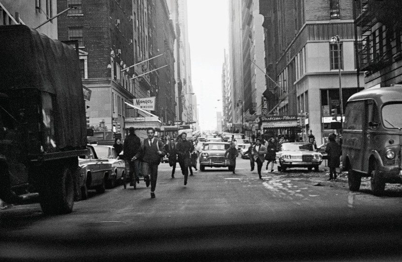 Fans on West 58th Street, crossing 6th Avenue, photographed through the rear car window 
