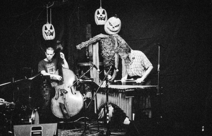 Black and white photo of a band playing music surrounded by jack-o-lanterns