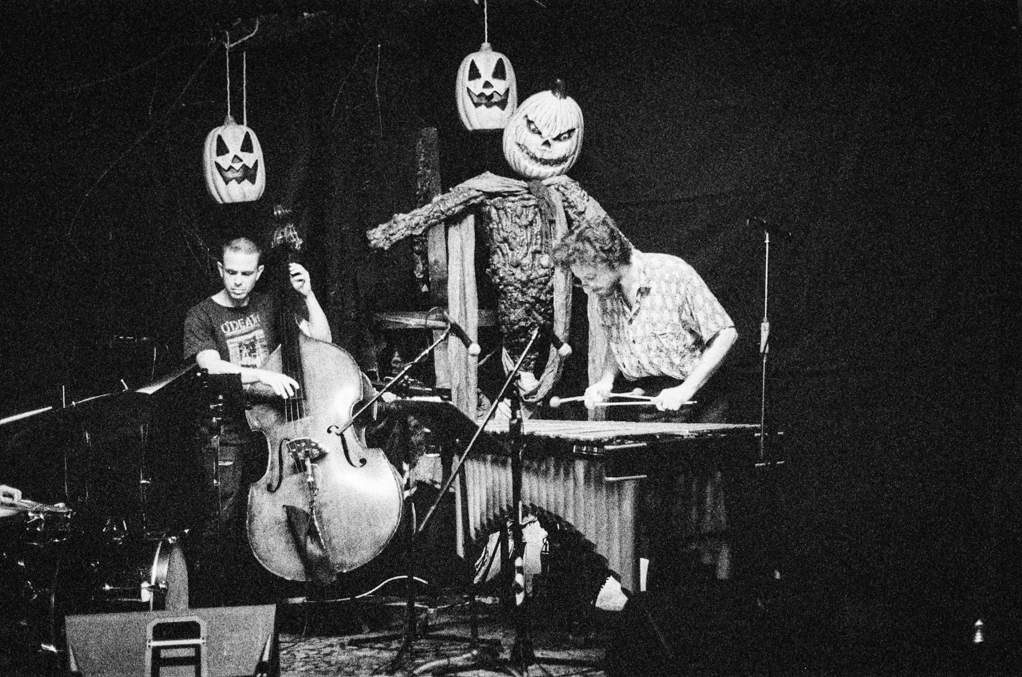 Black and white photo of a band playing music surrounded by jack-o-lanterns