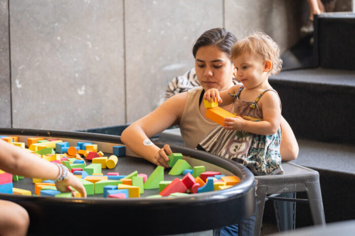 A woman plays with blocks with a toddler.