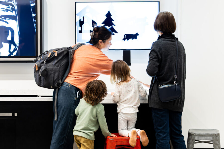 Two women look at a stop motion station with two small children.