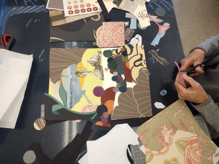 A person's hands cut pieces of paper for a collage.