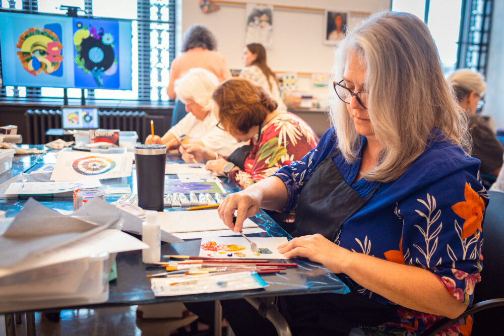 A woman paints in an art classroom.