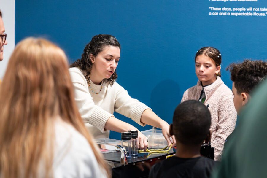 A woman shows students different materials at sensory station.