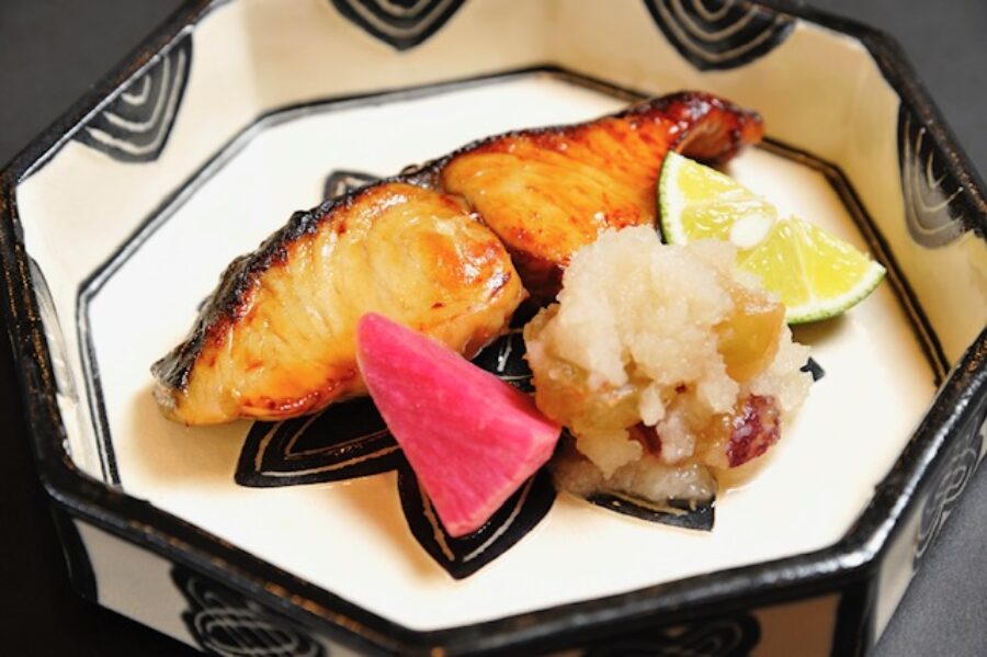 A bowl of Japanese-style fish, rice and fruits.