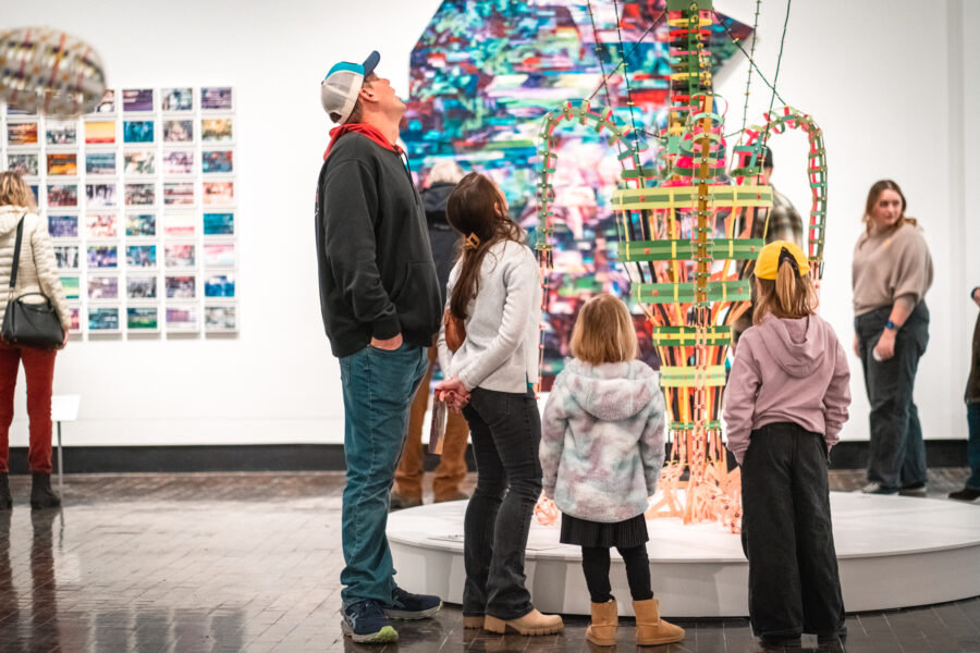A man and three children look at a sculpture in an art gallery.