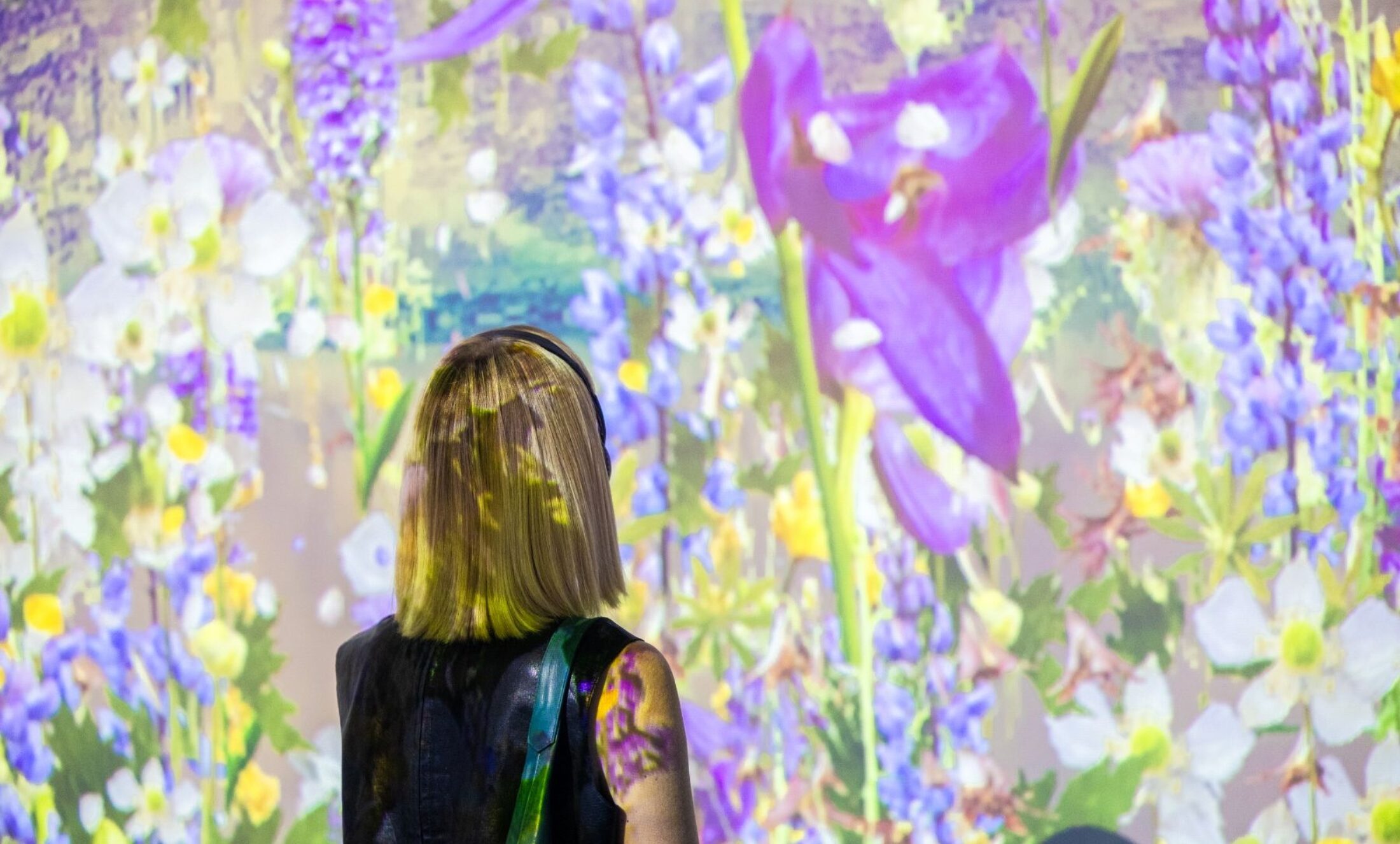 Woman looking at a colorful flower projection