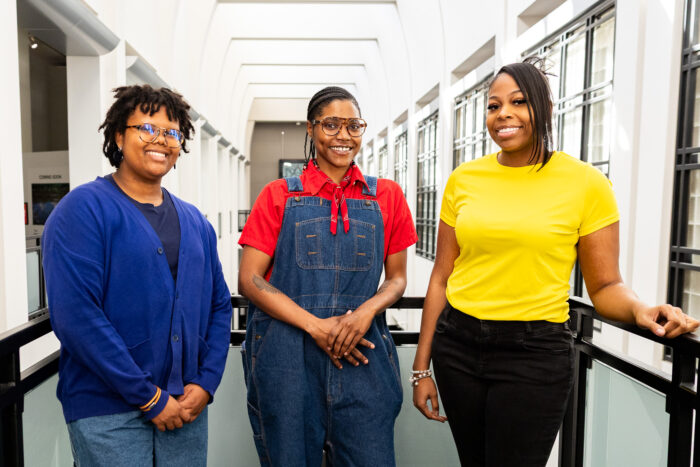 Three woman pose for a photo together in a museum.