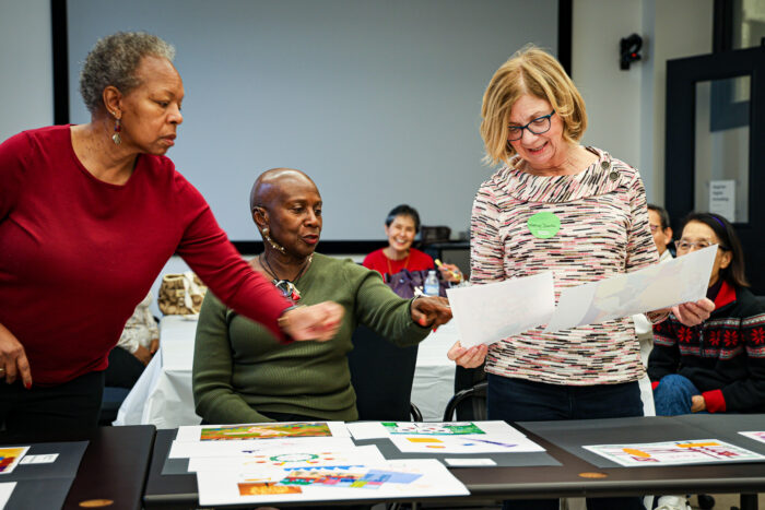Three women look at digital art pieces together.