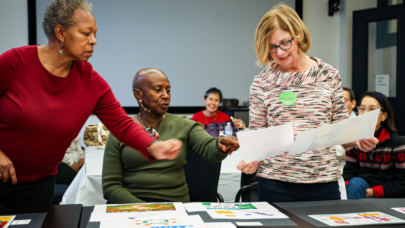 Three women look at digital art pieces together.