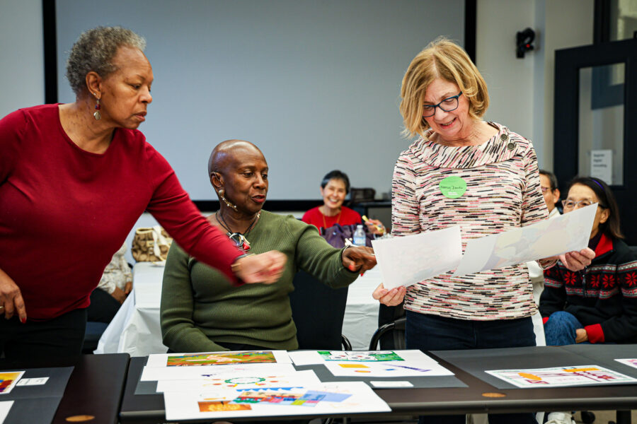 Three women look at digital art pieces together.