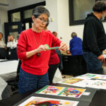 A woman takes a photo on her phone of digital artwork.