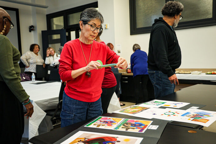 A woman takes a photo on her phone of digital artwork.