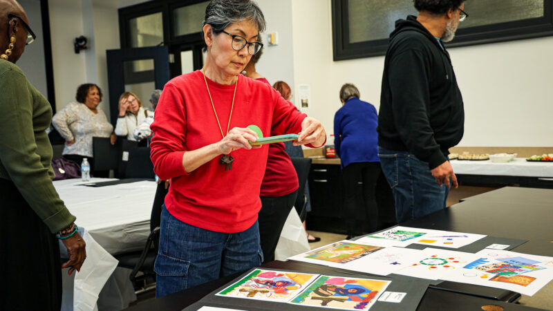 A woman takes a photo on her phone of digital artwork.