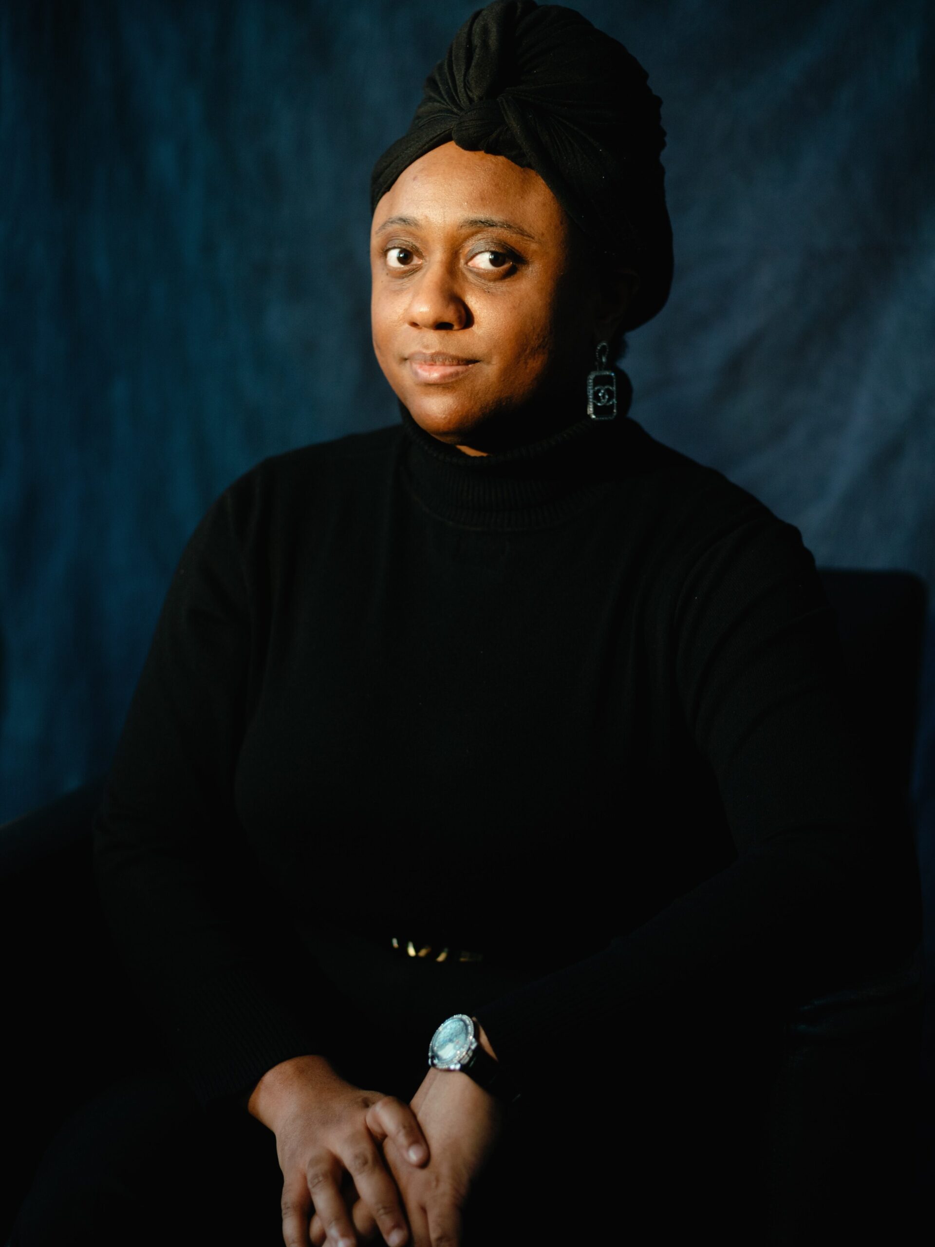 The artist Ashley Doggett poses for a headshot in an all black outfit.