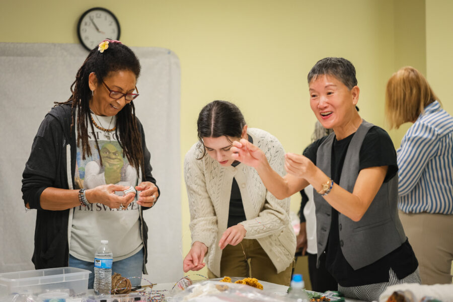 A group of women gather around a table with various textiles.