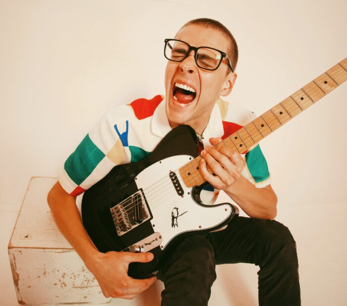 A photo of a man yelling with excitement with a guitar.