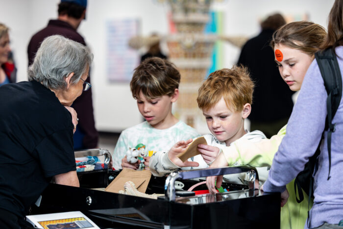 Three kids look at items on a table.