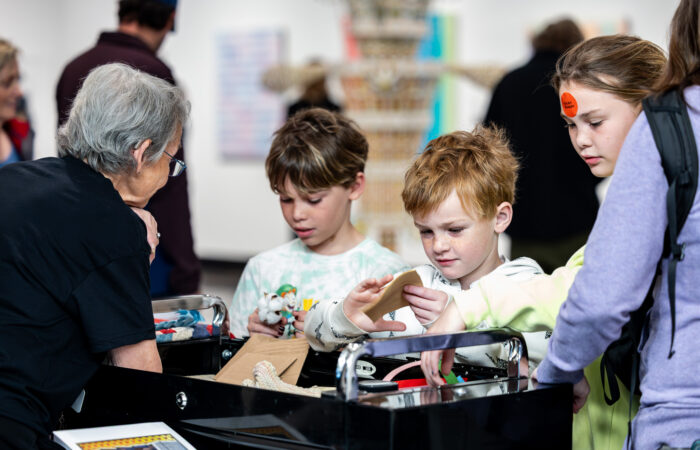 Three kids look at items on a table.
