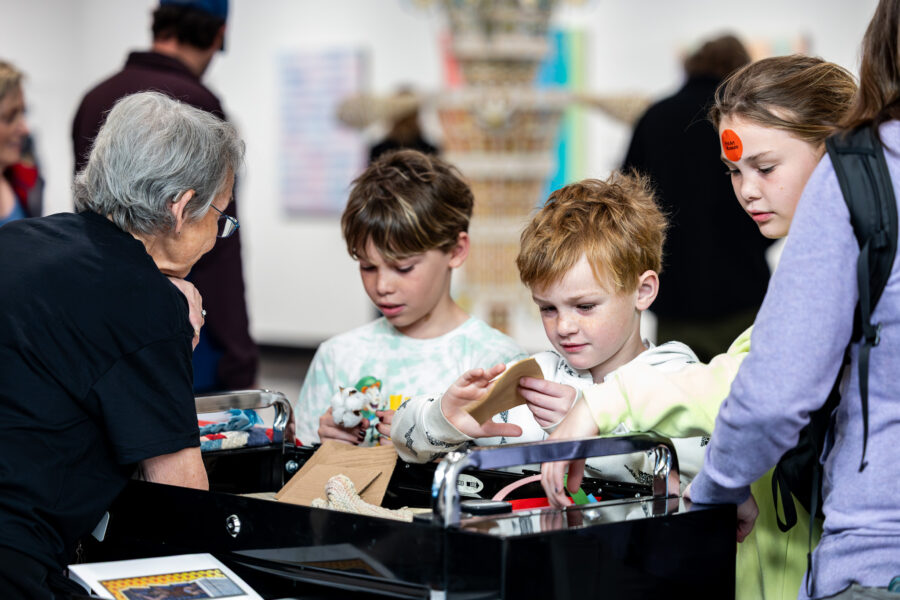 Three kids look at items on a table.