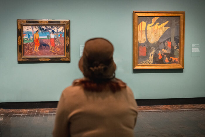 Woman sitting and looking at two Impressionist paintings.