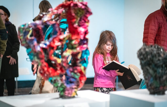 A young girl draws in a journal in an art gallery.
