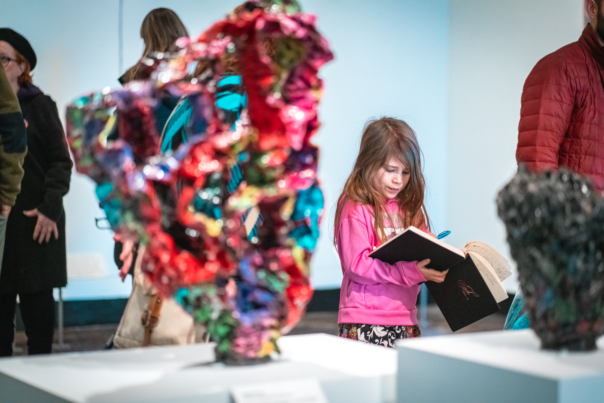 A young girl draws in a journal in an art gallery.