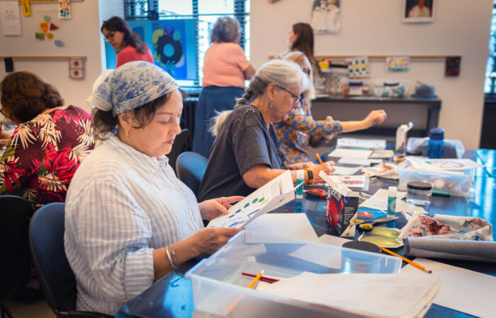 A group of women paint in an art studio.