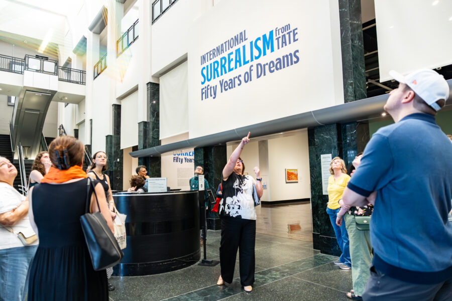 Woman pointing up explaining about the museum to a group of people.