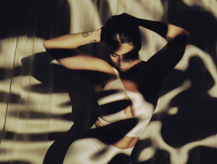A woman poses in a pattern created by shadows.