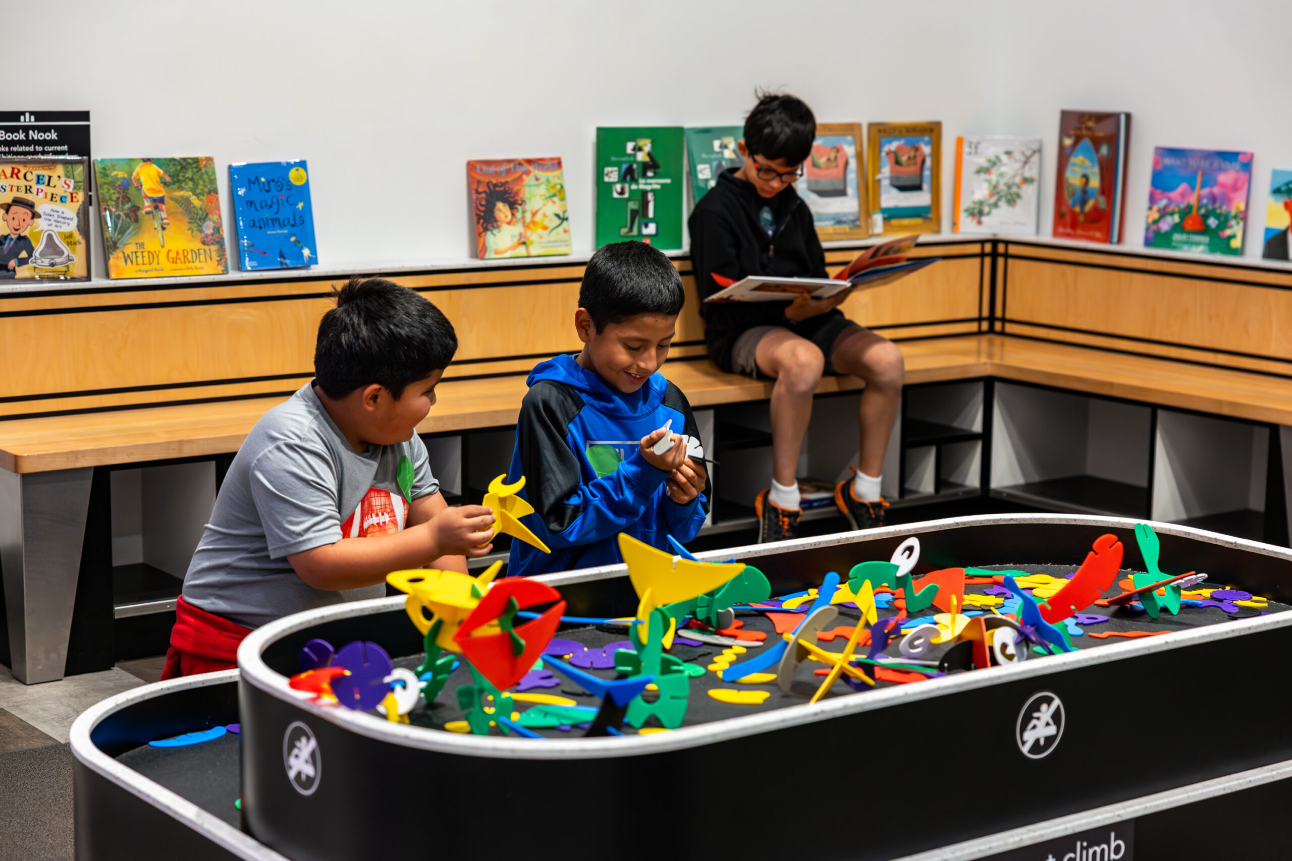 Three boys play with blocks and books.