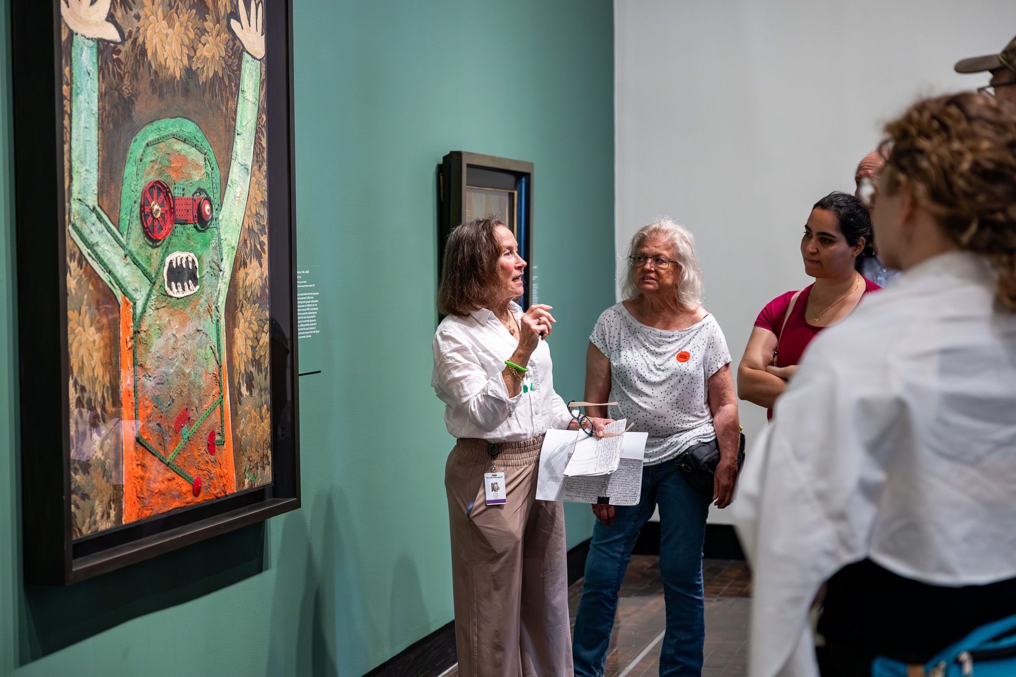 A woman leads a tour in an art gallery of surrealist paintings.