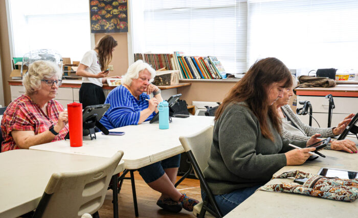 Four women work on an iPad in an art class.