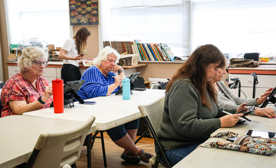 Four women work on an iPad in an art class.
